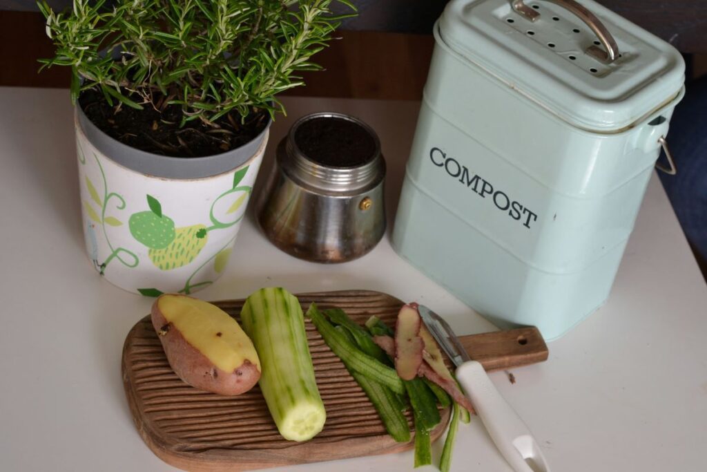 Plant based food items next to a compost bin on a counter.