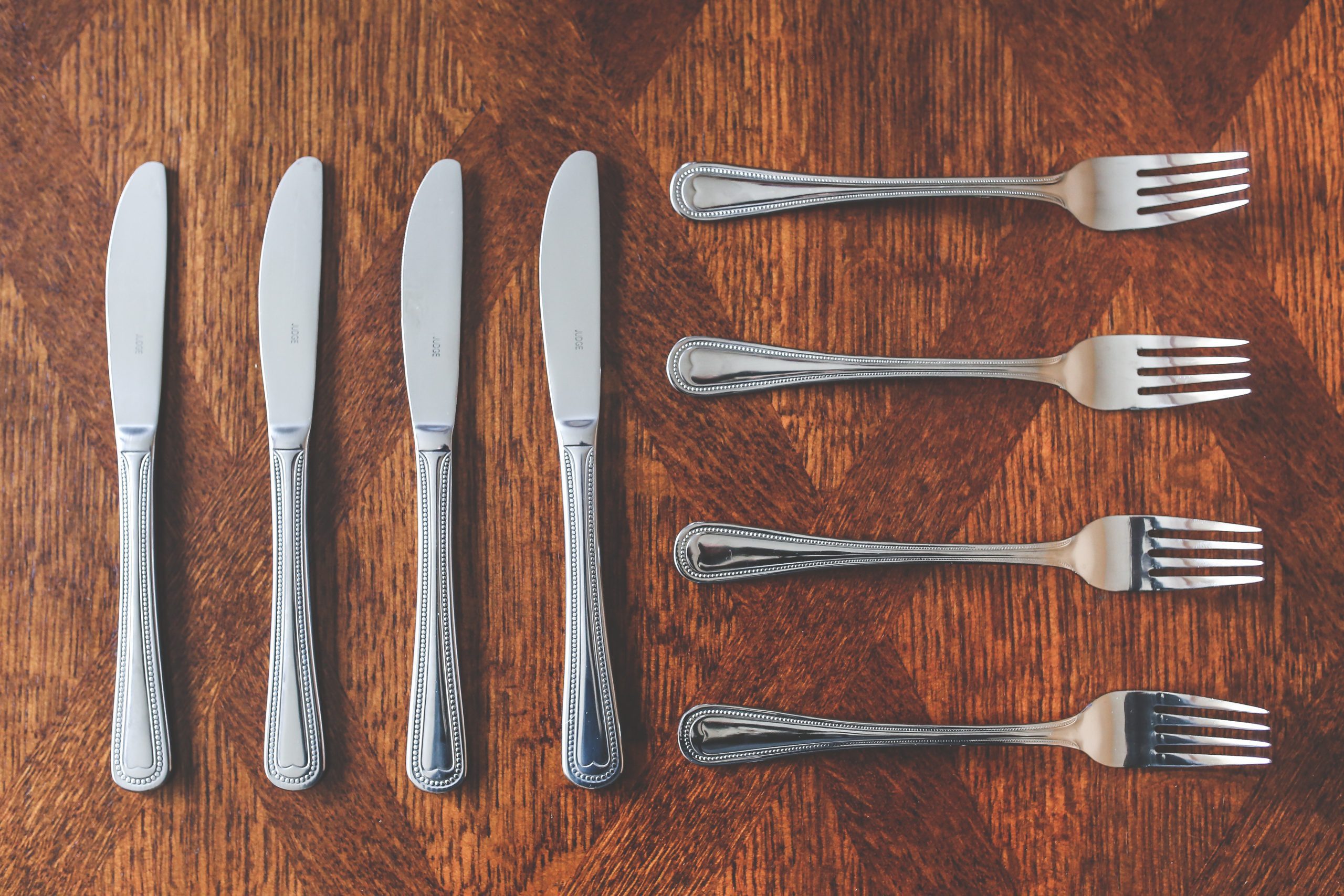 four knives and four forks on a wooden backdrop