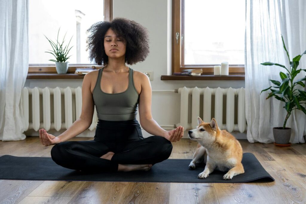 Woman meditating on a yoga mat with a dog